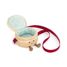 A plush cake-shaped bag with cream-colored frosting, red cherry details, a striped candle, and a red strap, shown on a plain white background. Open view. 
